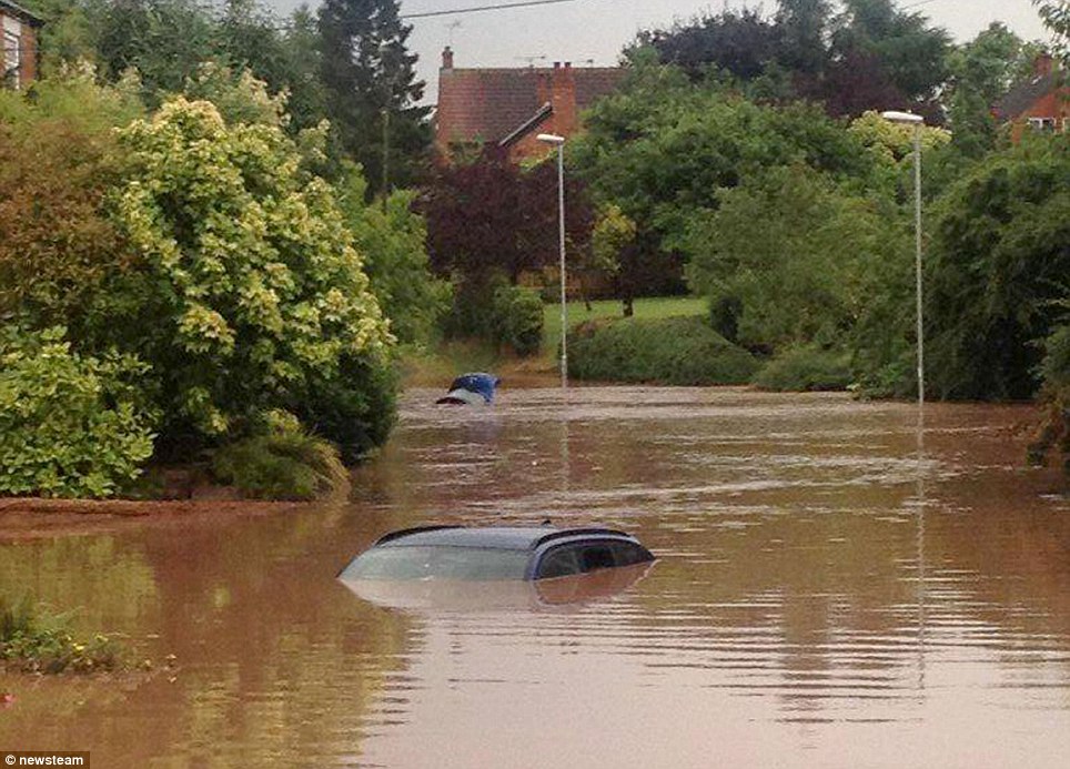 © newsteam Summer soaking: A car is almost completely covered by muddy water after a downpour caused flash flooding in Southwell, Nottingham, yesterday